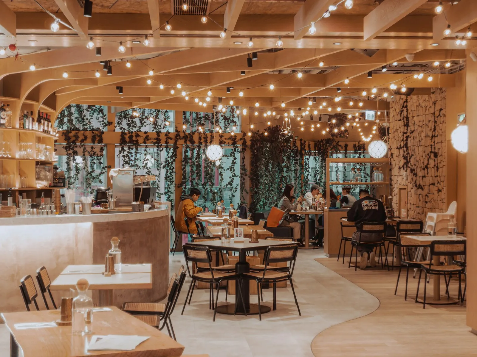 Salón de un restaurante con mesas de madera y luces cálidas colgando del techo